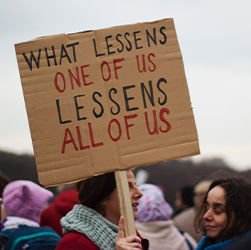 sign saying what lessens one of us lessens all of us